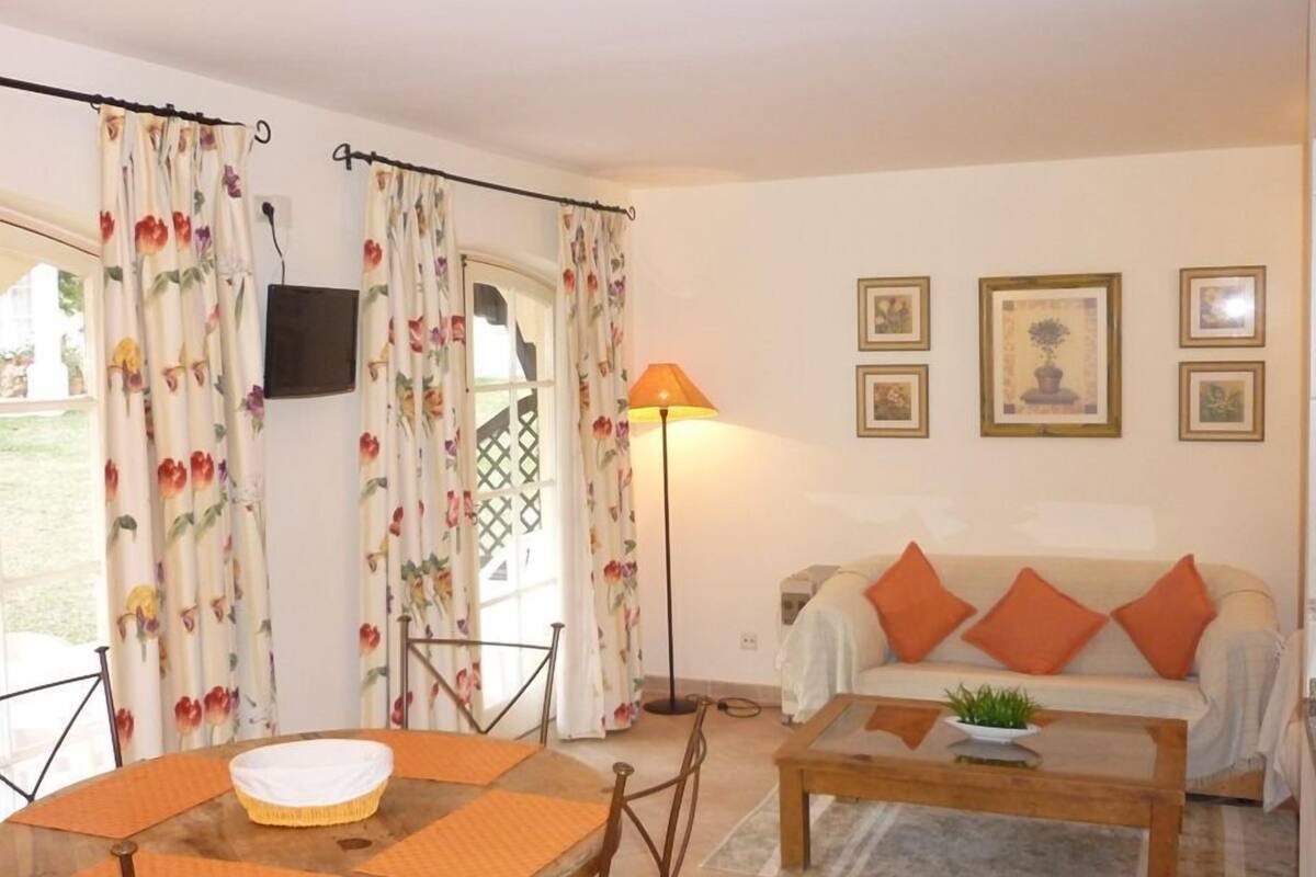 Een woonkamer met een bank, salontafel en gordijnen.