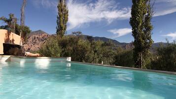Una piscina al aire libre, sombrillas, sillones reclinables de piscina