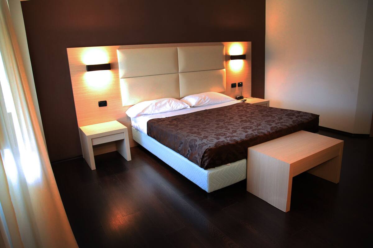 Un dormitorio moderno con una cama grande, mesitas de noche y un banco.