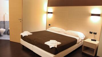 Une chambre d’hôtel avec un lit, une table de chevet et une petite table d’appoint.