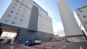 A multi-story hotel with a prominent entrance and a parking area with marked spaces and traffic cones.