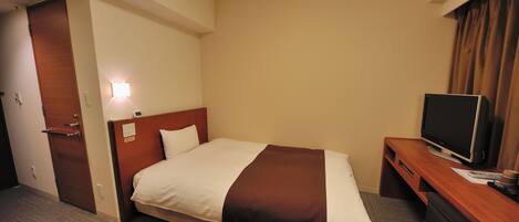 A hotel room with a bed, a TV, a desk, and a door.
