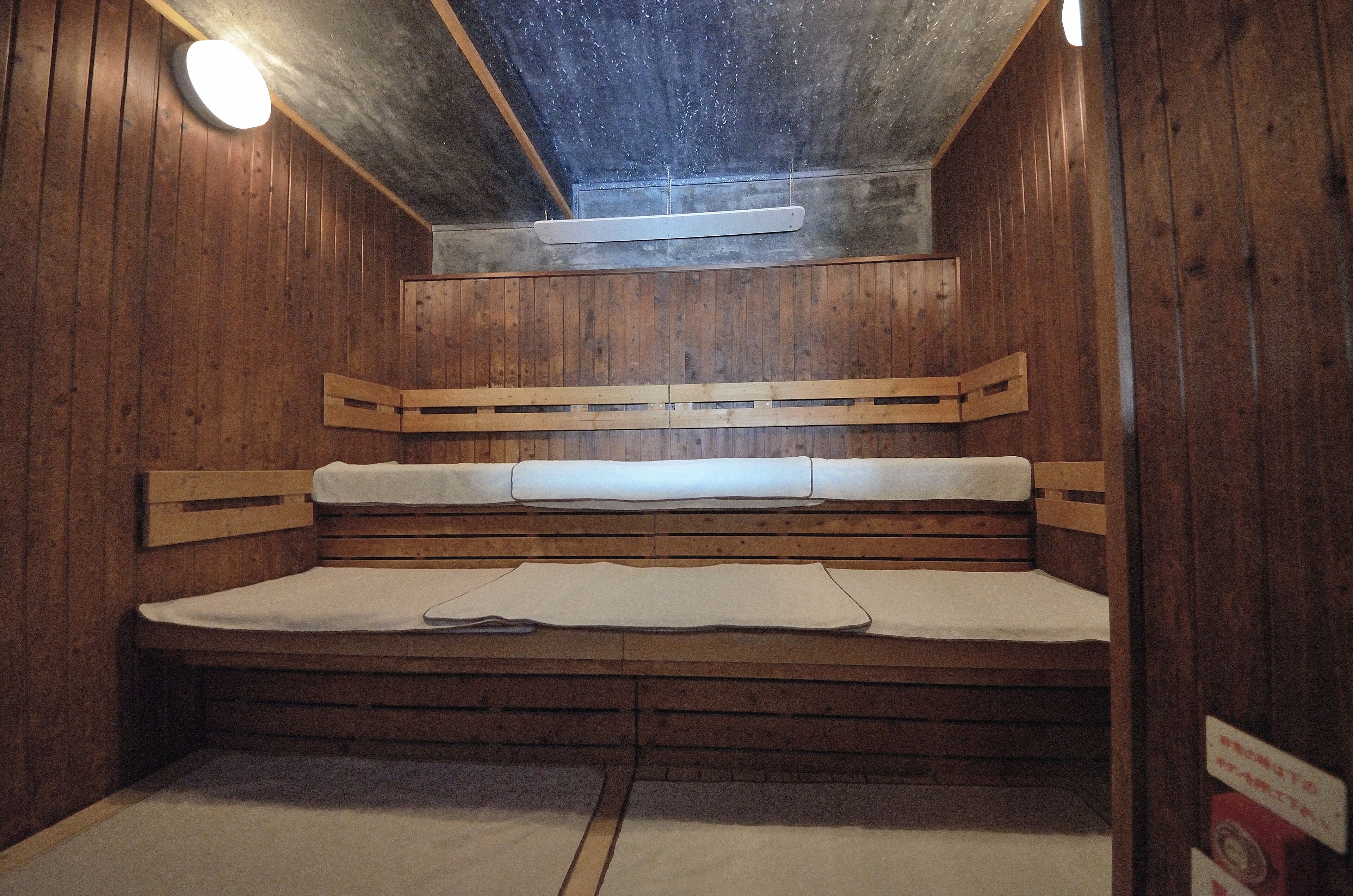 Una sauna con pareti in legno, una panca e una luce al soffitto.