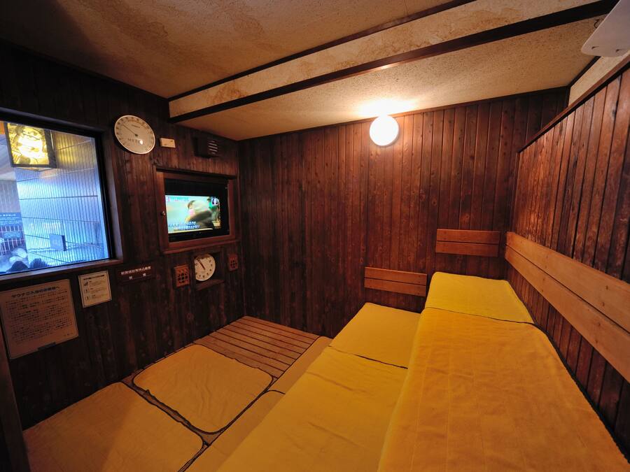 A wooden room with a bed, a clock, a television, and a window.