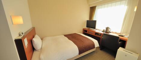 A hotel room with a bed, a desk, a television, and a mini-fridge.