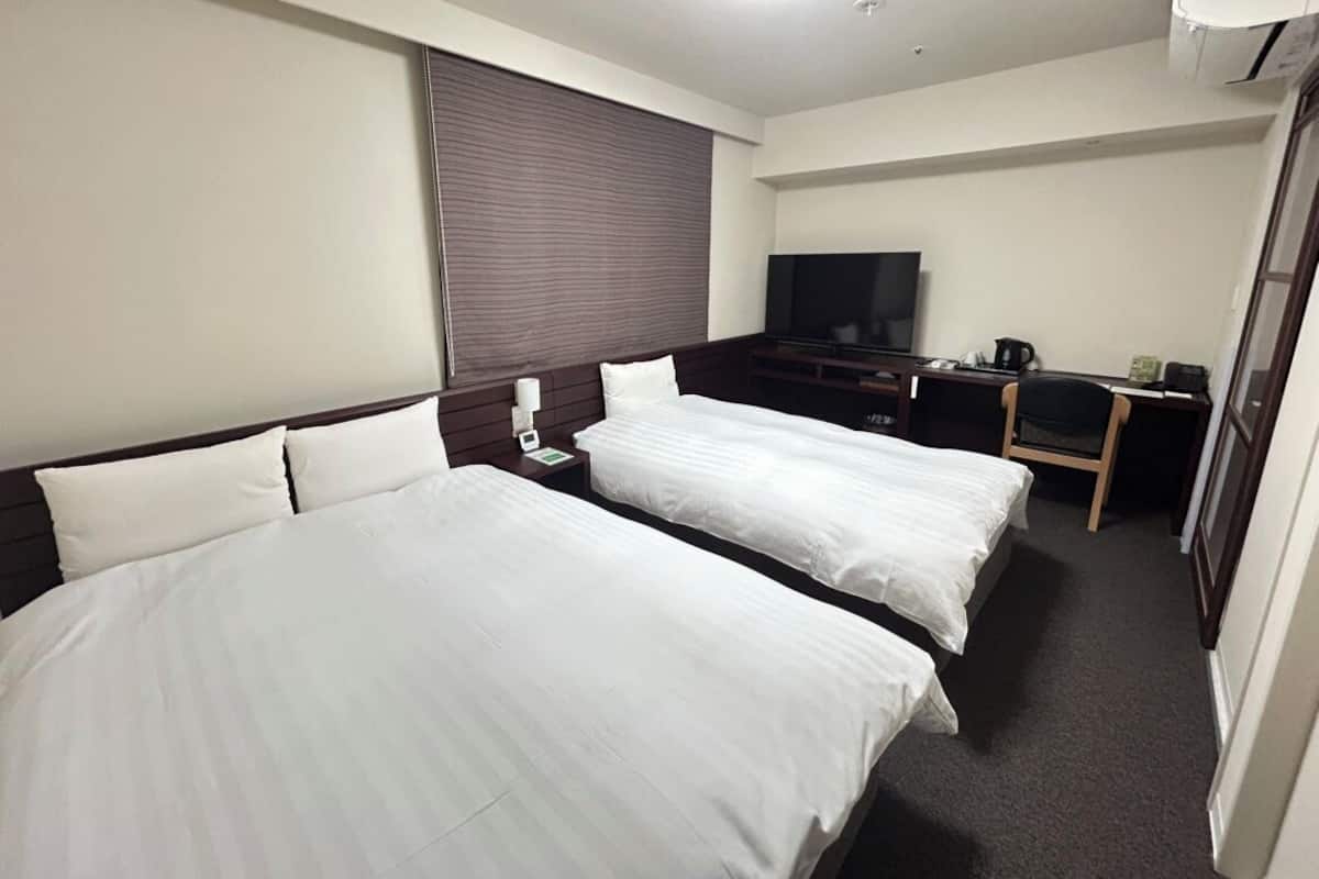 Ett hotellrum med två sängar, en TV, ett skrivbord och en kaffebryggare.
