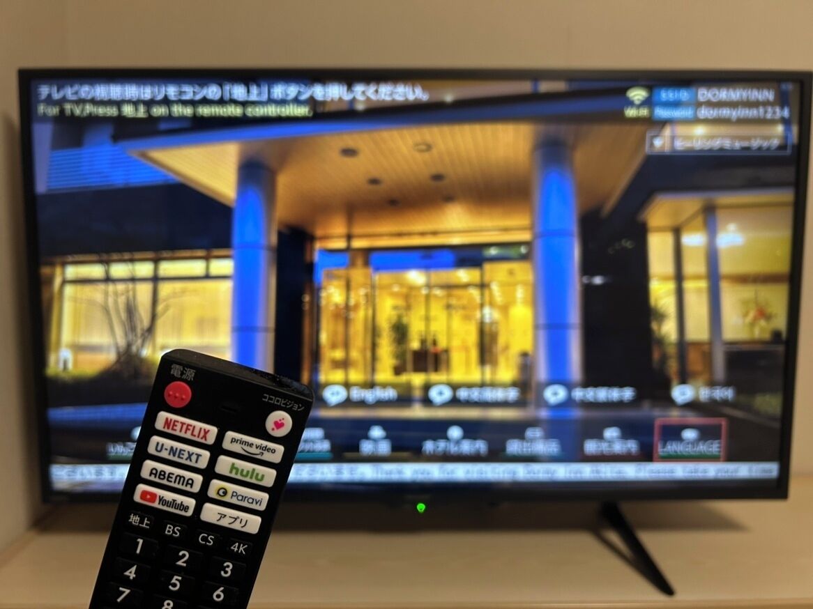 Un televisor muestra un hall de hotel con un control remoto al frente.
