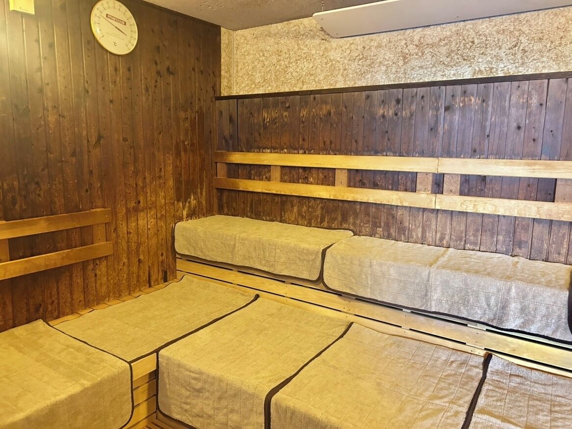 Ein Saunaraum mit Holzbänken und Bänken, die mit beigefarbenen Handtüchern ausgelegt sind.