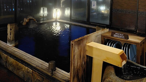 A hot spring bath with a view of the city at night, wooden interior, and a sign indicating the bath's name. - Dormy Inn Akita Natural Hot Spring (Akita)