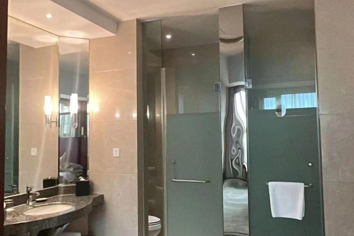 A modern bathroom with a glass-enclosed shower, a sink, and a mirror.