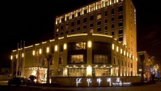 A multi-story hotel with a curved facade, illuminated windows, and a sign in both Chinese and English. - Yuloon Hotel Shanghai (Shanghai)