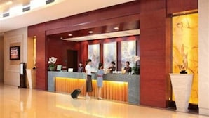 A hotel reception area with a wooden reception desk, a large vase, and a framed picture on the wall. - Yuloon Hotel Shanghai (Shanghai)