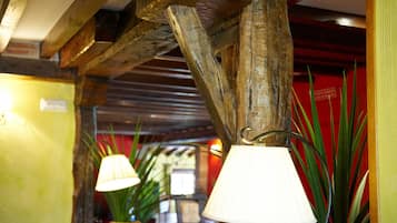 A rustic interior with exposed wooden beams, a hanging lamp, and a potted plant.