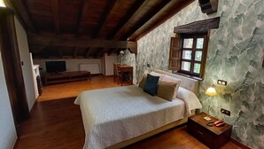 A bedroom with a bed, bedside table, lamp, and a window with curtains. - La Casona de Revolgo (Santillana del Mar)