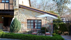 A stone building with outdoor seating, a café sign, and a large umbrella. - La Casona de Revolgo (Santillana del Mar)