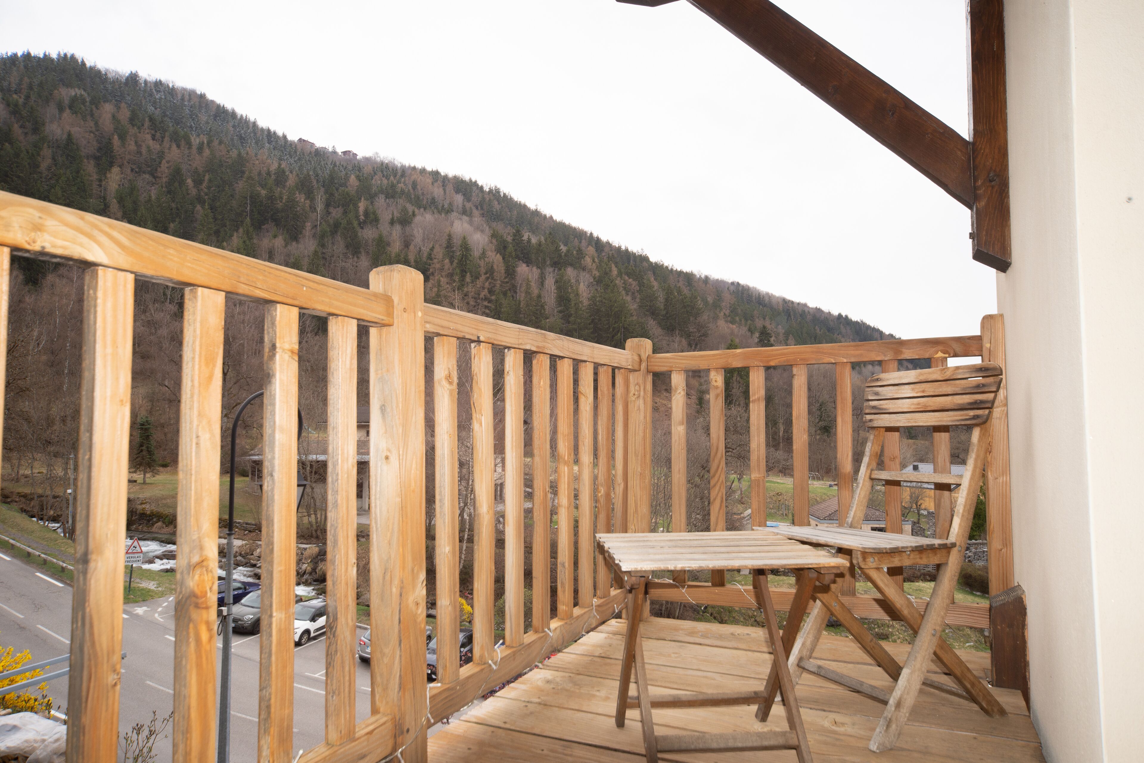 Een houten balkon met uitzicht op een weg en bergen.