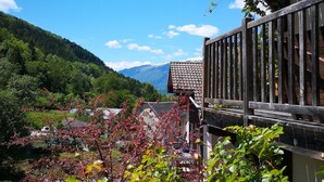 A mountain village with traditional wooden buildings, a clear blue sky, and a view of the surrounding hills. - Maison Caramel (Landry)