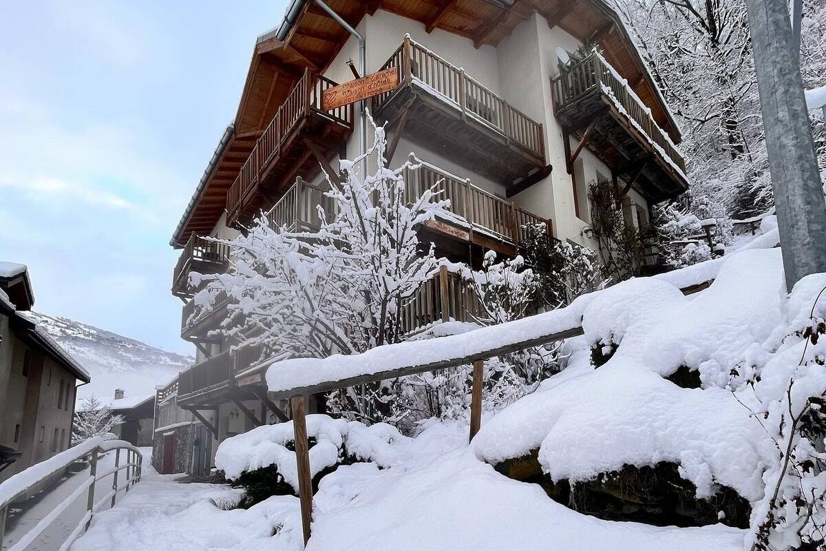 Un bâtiment enneigé, doté de nombreux balcons et d’un escalier en bois.
