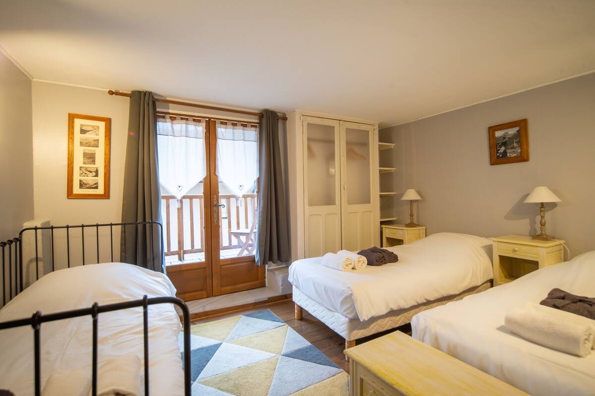 Une chambre d’hôtel avec deux lits, une armoire en bois, une petite table et une fenêtre avec des rideaux.