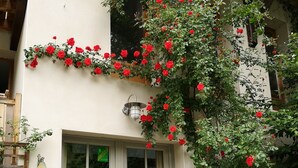 A building with a white facade, a wooden door, and a stone wall. - Maison Caramel (Landry)