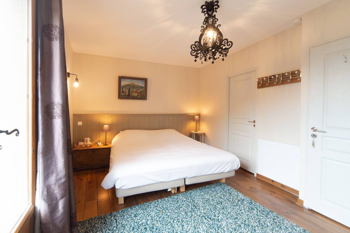 Une chambre à coucher avec un lit, des lampes de chevet, une table de chevet, une porte et un tableau accroché au mur.
