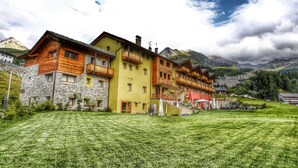 A row of colorful buildings with balconies, set against a mountainous backdrop. - Hotel La Chance (Gressan)