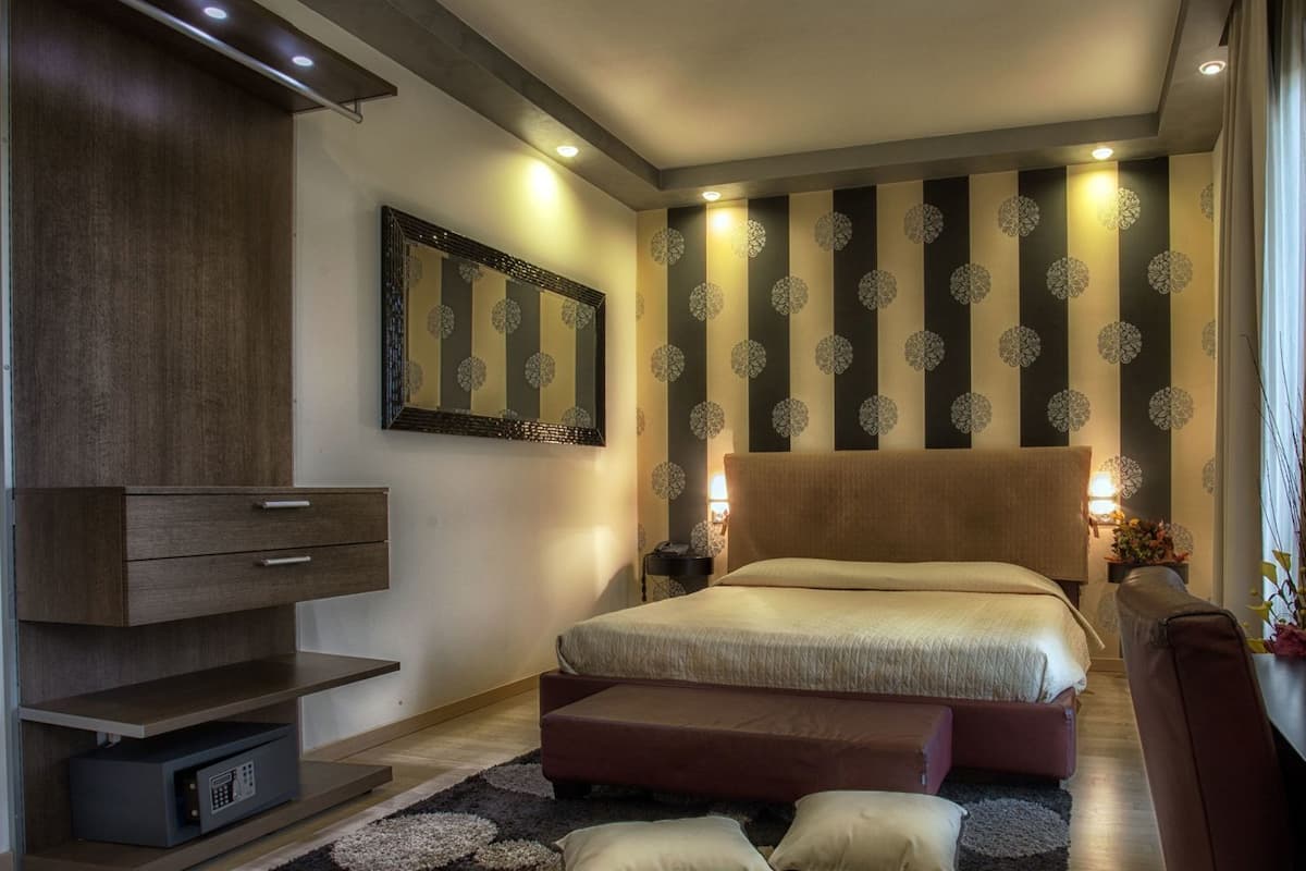 A modern bedroom with a large bed, a TV, and a decorative mirror.