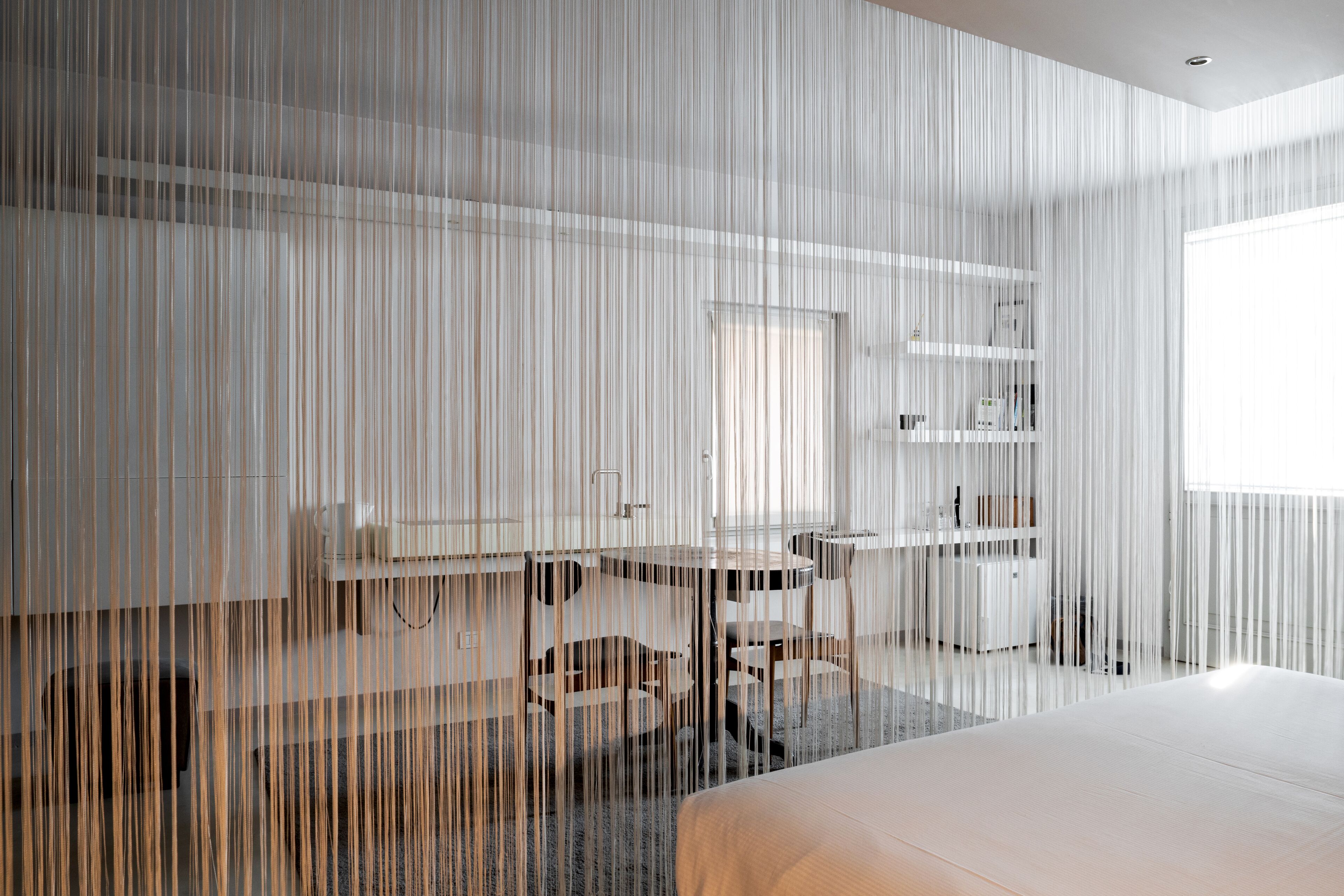 Een moderne hotelkamer met een groot bed, een bureau en een stoel. Een raam zorgt voor natuurlijk licht.