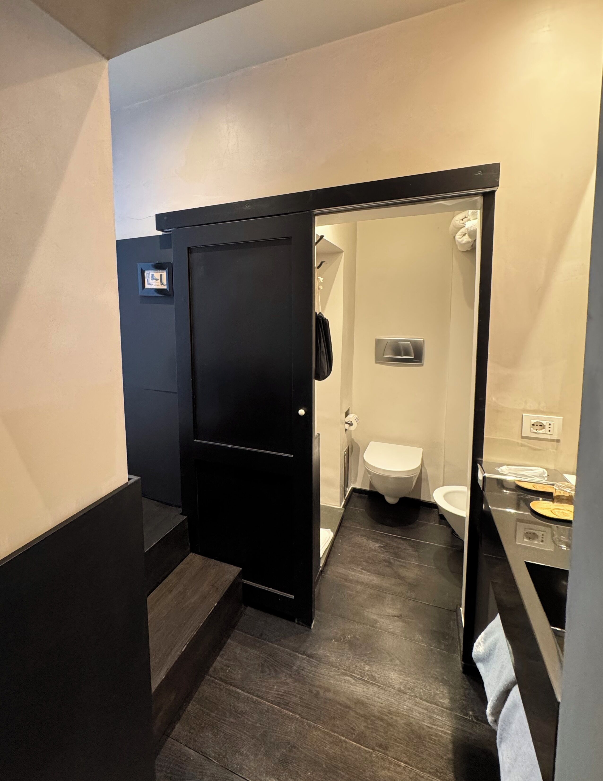 Un baño moderno con una puerta negra, un inodoro y una zona de ducha.