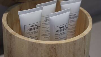 A wooden container holding several tubes labeled "REPLICA Body Cream" and "REPLICA Shower Gel."