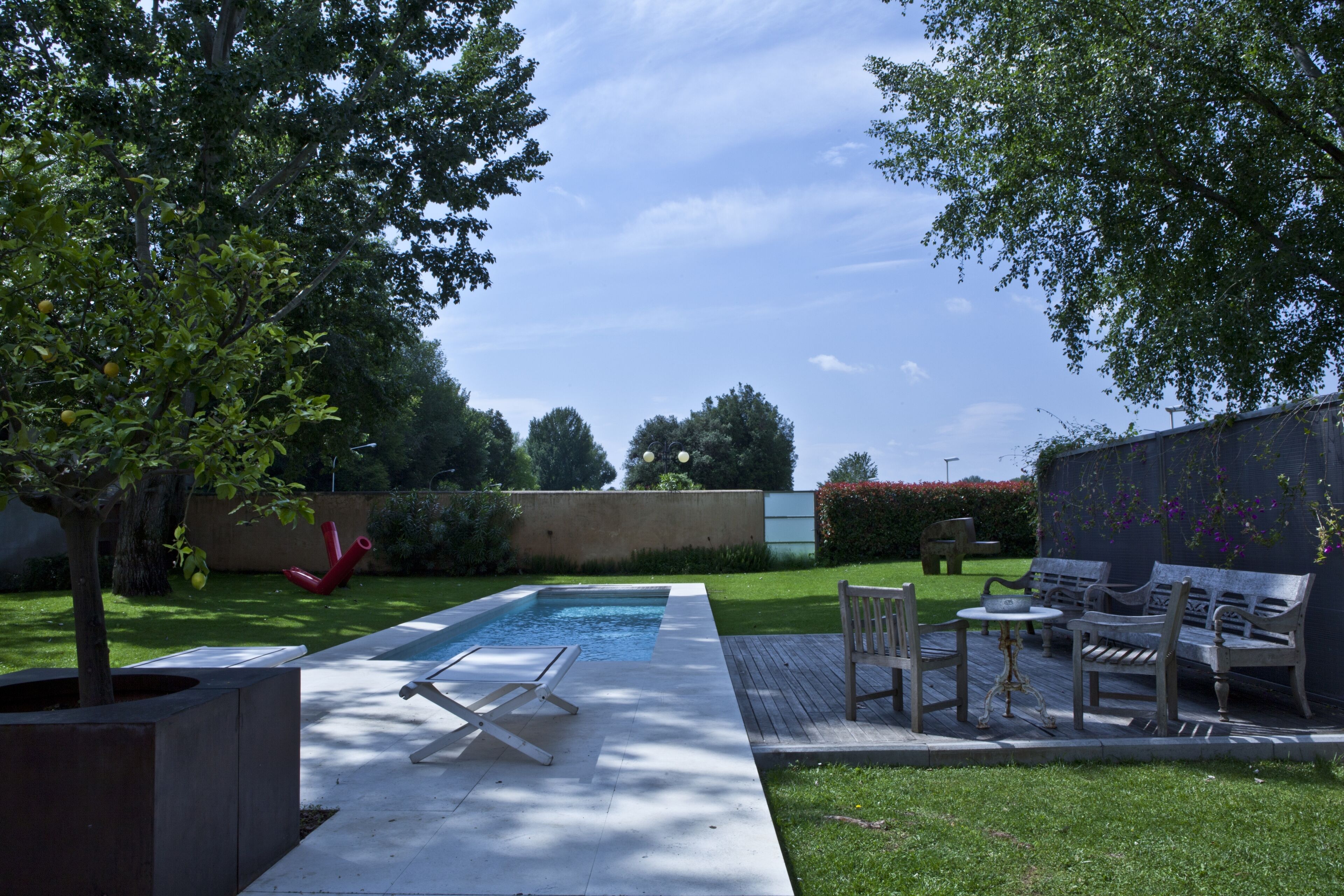 A backyard with a swimming pool, outdoor furniture, and a garden.