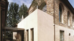 Un bâtiment moderne avec une façade en pierre, de grandes fenêtres et un patio couvert.