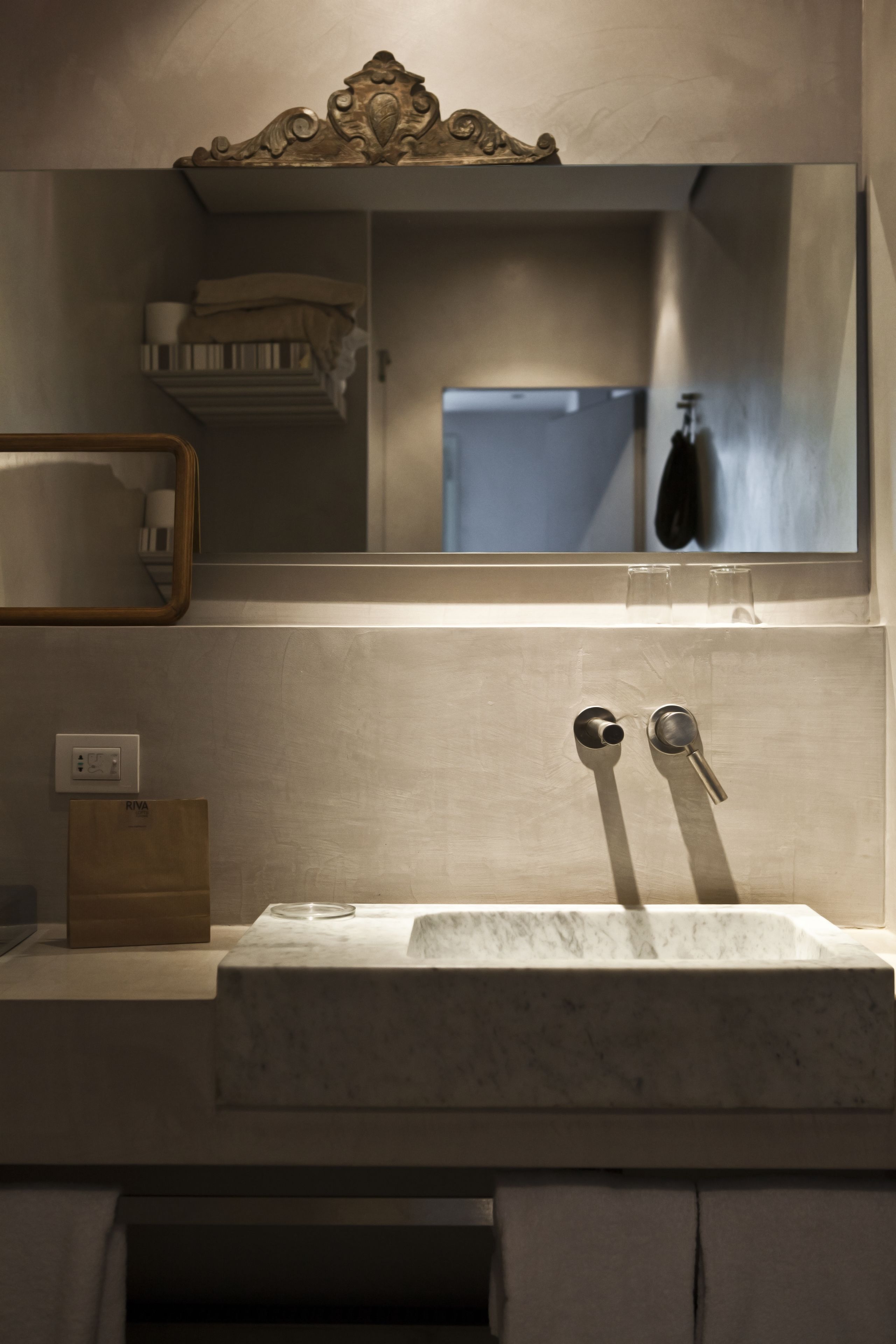 A bathroom with a marble sink, a mirror, and a towel rack.