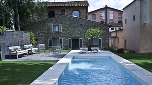 Une piscine avec un bâtiment en pierre en arrière-plan.