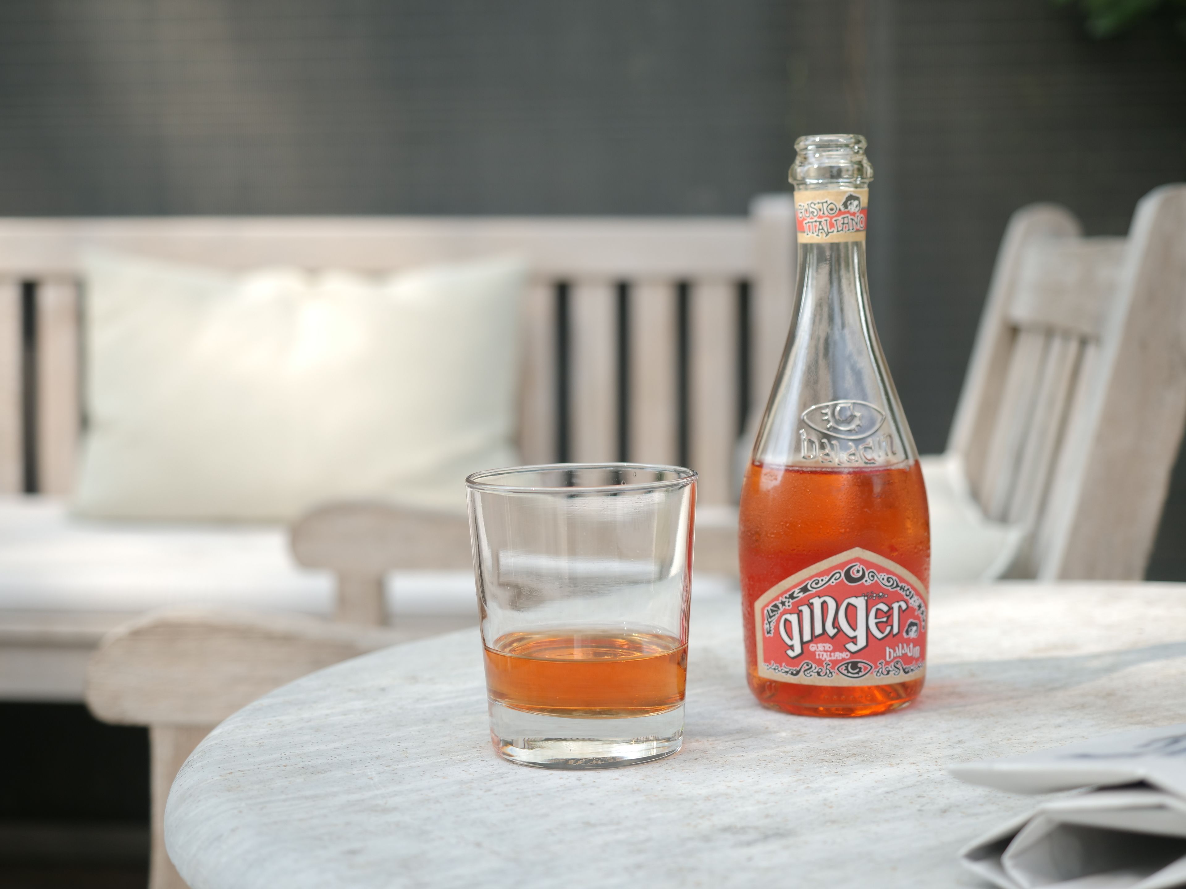 A bottle of ginger beer and a glass on a table.