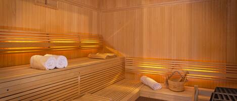 A wooden sauna with benches and benches, towels, and a wooden bucket.