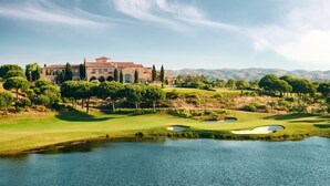 Una casa grande y lujosa con un campo de golf y un lago al frente.
