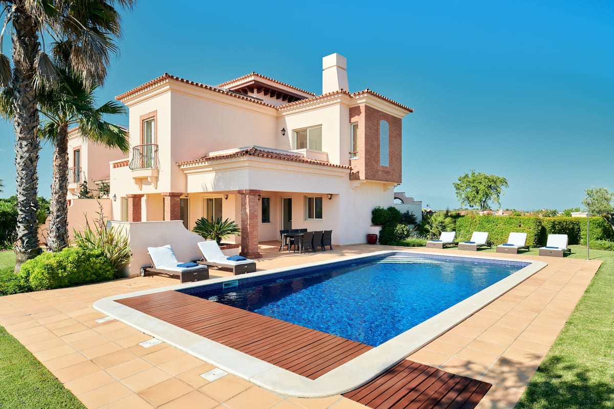 A modern house with a swimming pool, outdoor furniture, and a well-maintained garden.