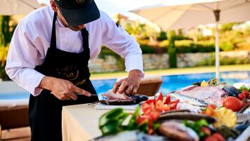 A chef preparing fish at a table with a pool in the background.