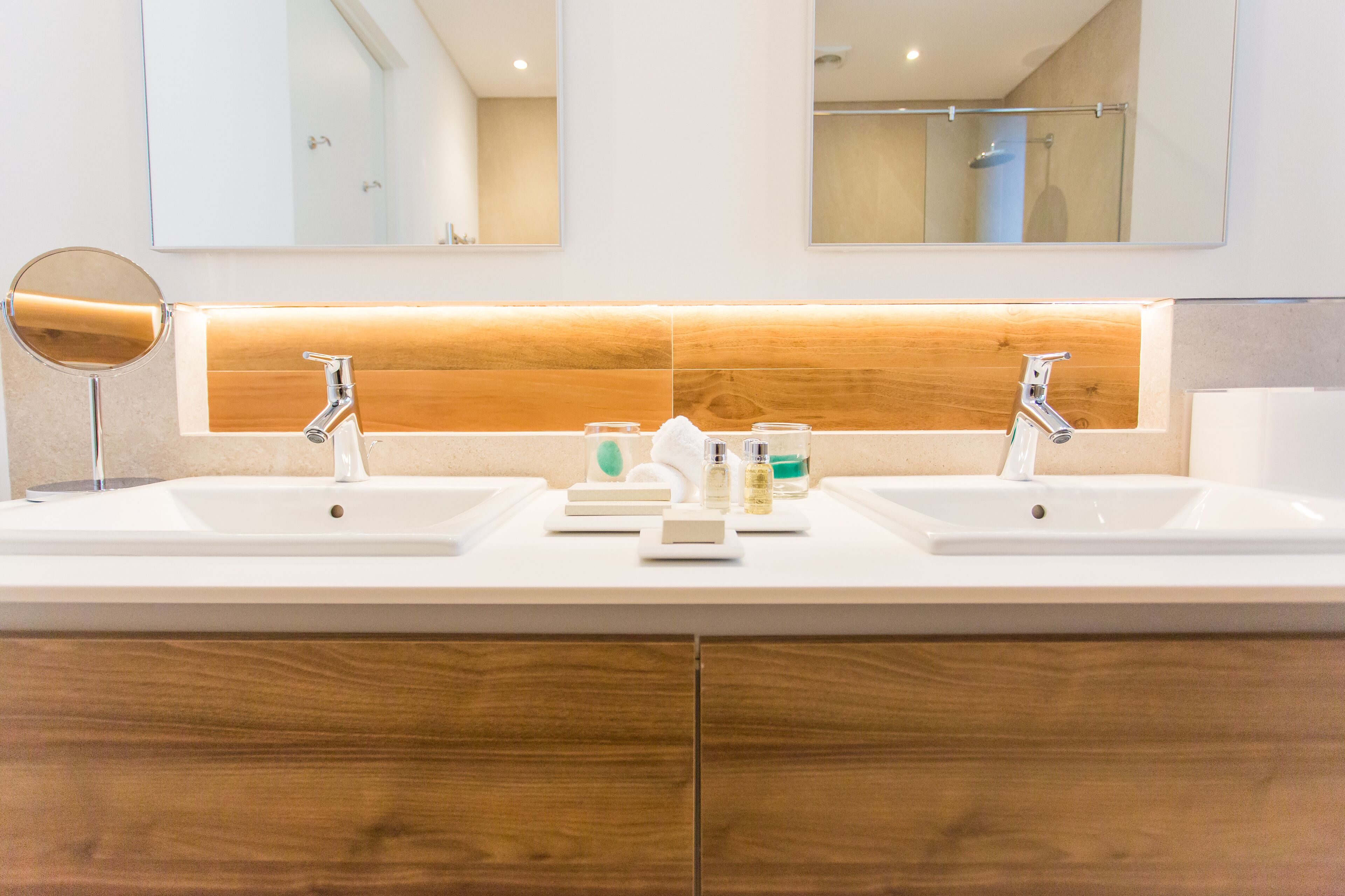 Un baño moderno con dos lavamanos, tocador de madera y un espejo.