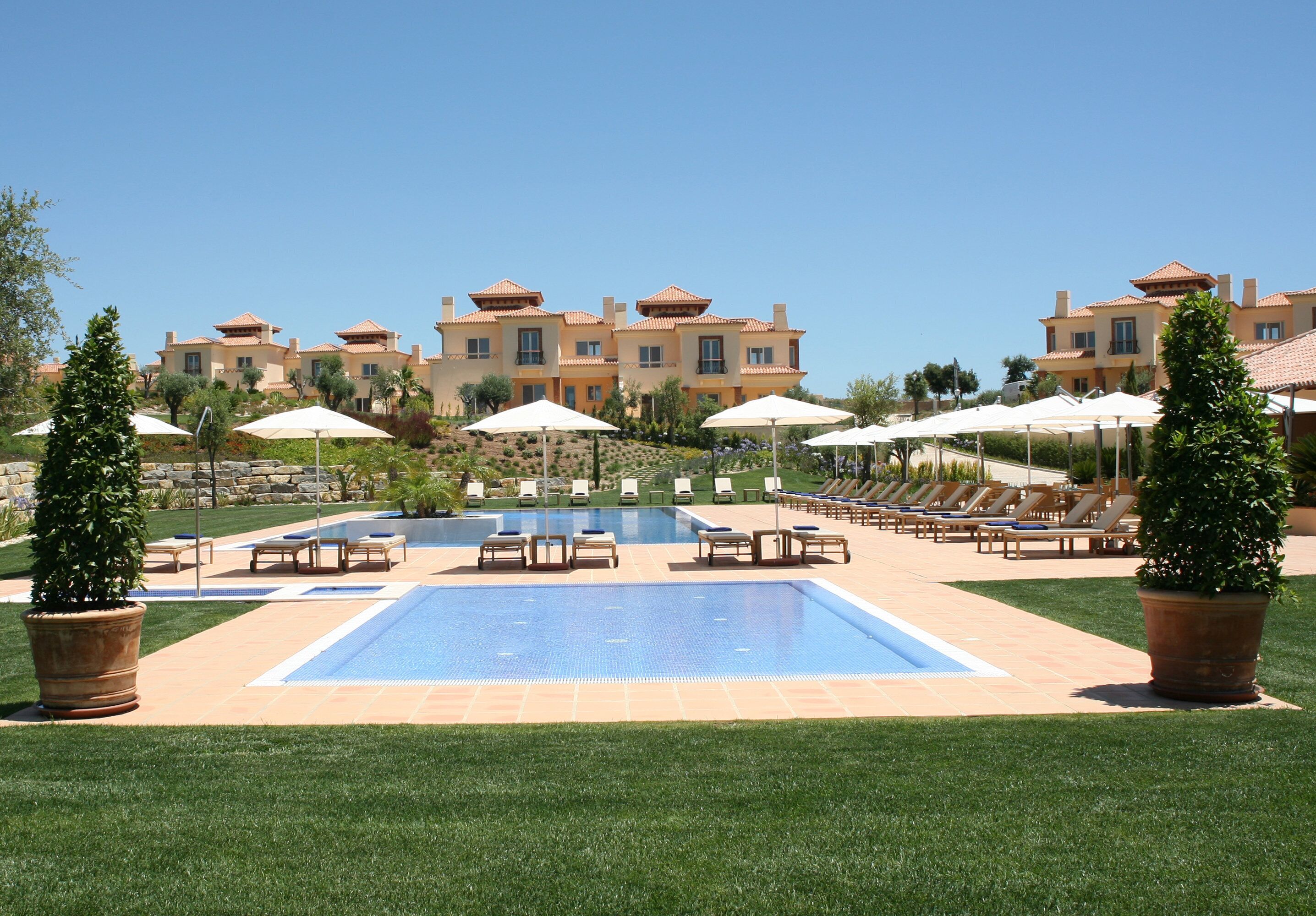 Um hotel com piscina, espreguiçadeiras e guarda-sóis.