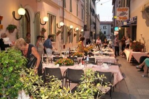 An outdoor dining area with tables set for guests, surrounded by buildings with traditional architecture and hanging lights. - Innocenti (Montecatini Terme)