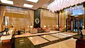 Eine geräumige Lobby mit Empfangstresen, Sitzgelegenheiten und einer großen Wand mit geometrischem Muster.