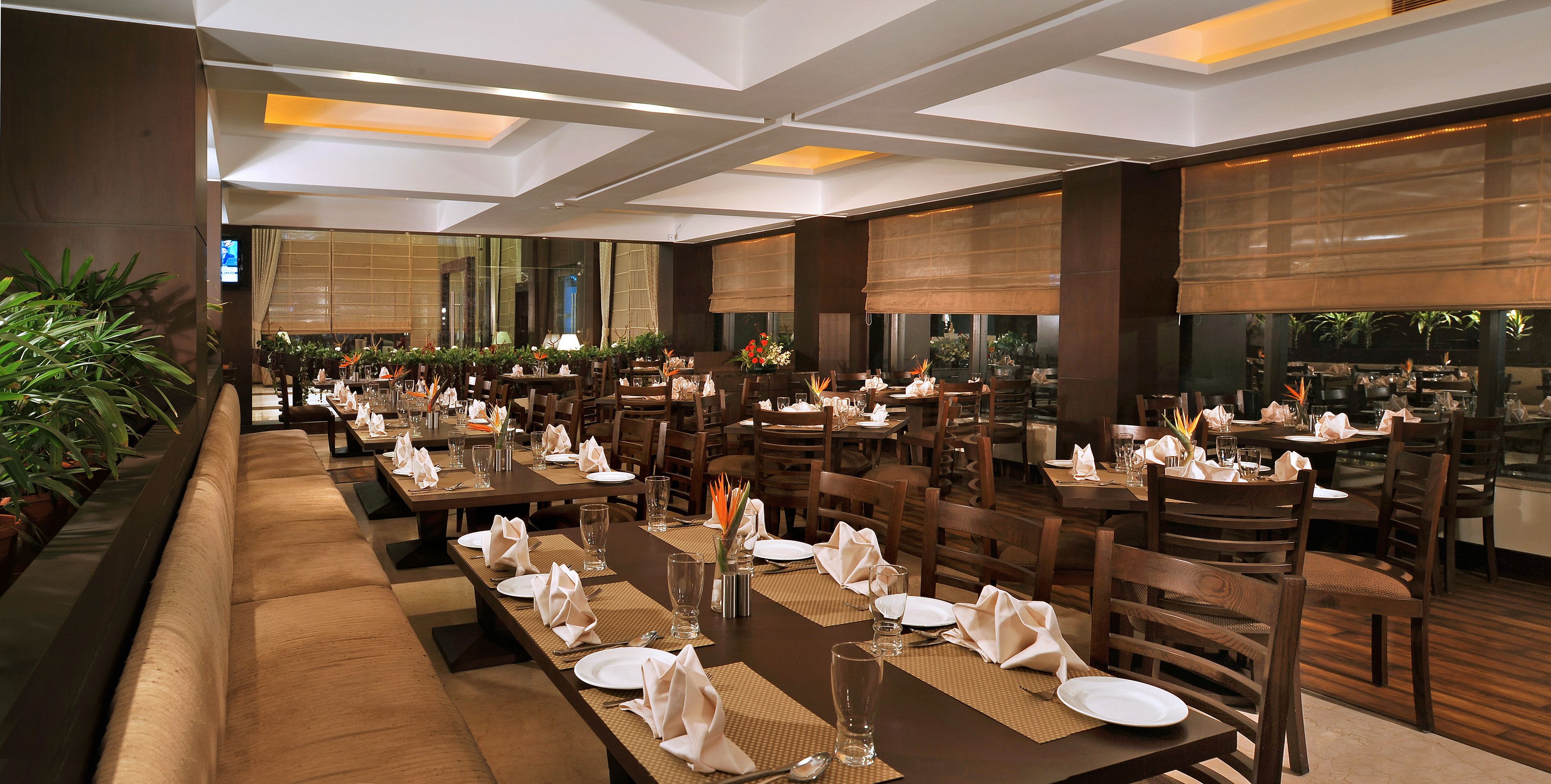 Un restaurant avec plusieurs tables, chacune mise avec des serviettes, des assiettes et des verres blancs.
