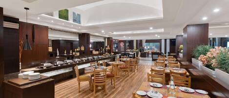 A spacious restaurant with a long counter, multiple dining tables, and wooden chairs.