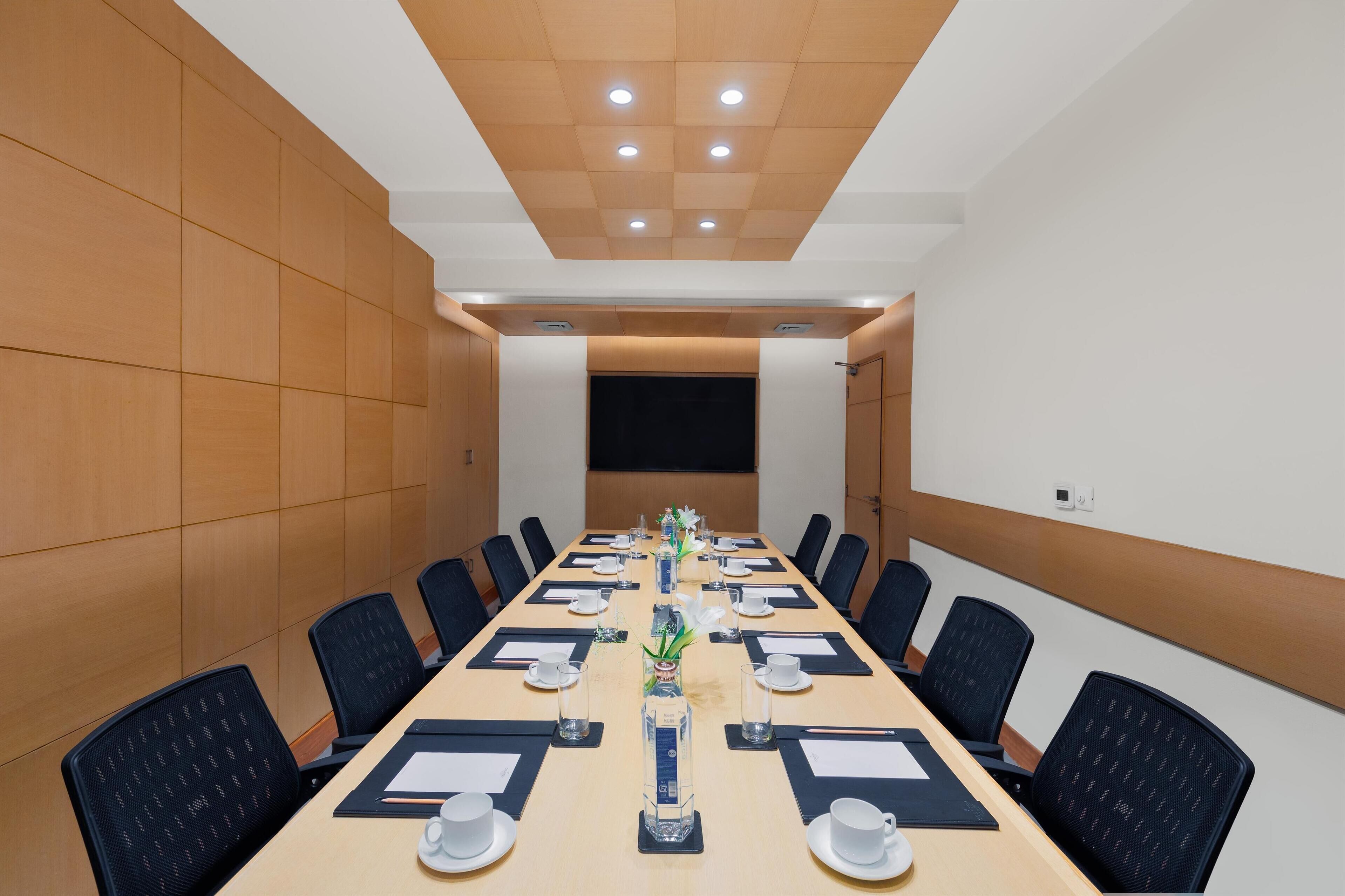 A conference room with a long table, black chairs, and a whiteboard at the front.