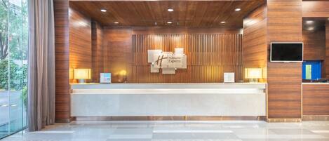 A reception desk with a wooden finish, a flat-screen TV, and a sign reading 'Holiday Inn Express'.
