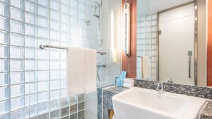 Un baño moderno con cabina de ducha de vidrio, lavamanos de mármol y un espejo grande.