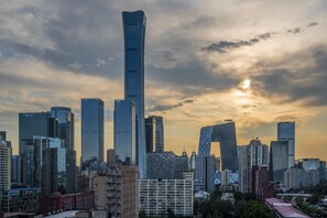 Paisagem urbana com arranha-céus modernos e um edifício imponente com topo curvilíneo.