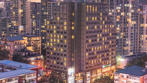 Un hotel de gran altura con numerosos pisos, amplias ventanas y un llamativo letrero de 'Holiday Inn Express'.